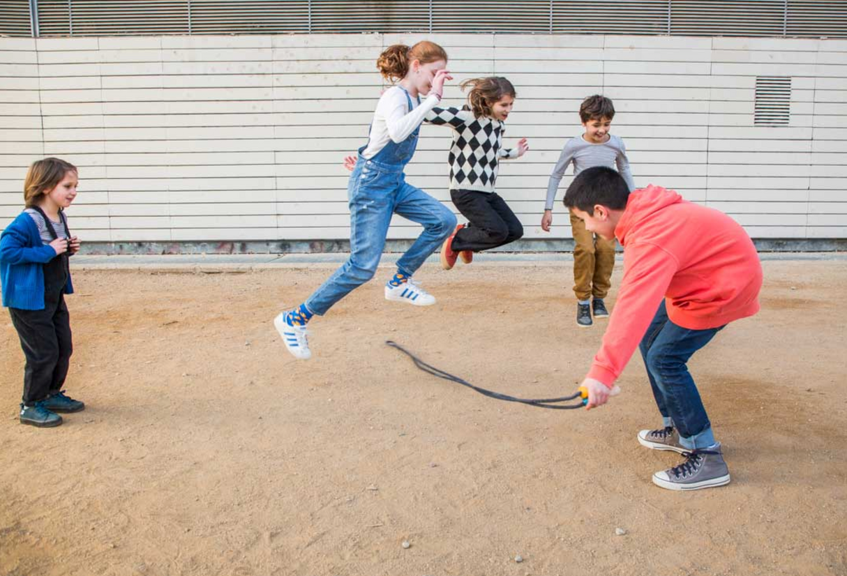 Children playing jump rope | Playground Coral & Mint outdoors on a sunny day with joyful energy.