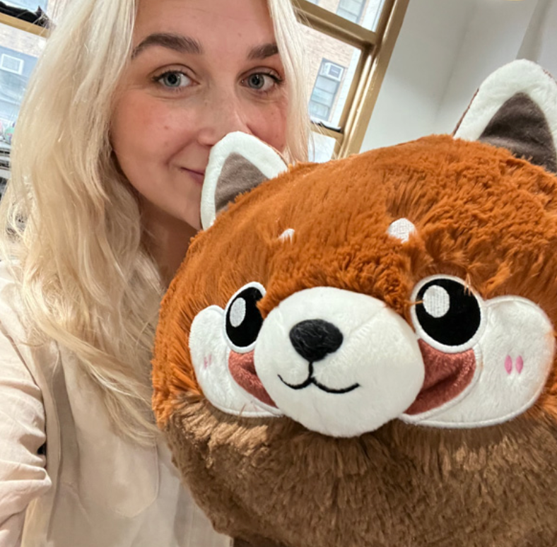 Woman holding a large plush Baby Red Panda with soft polyester fiber in a cozy indoor setting.