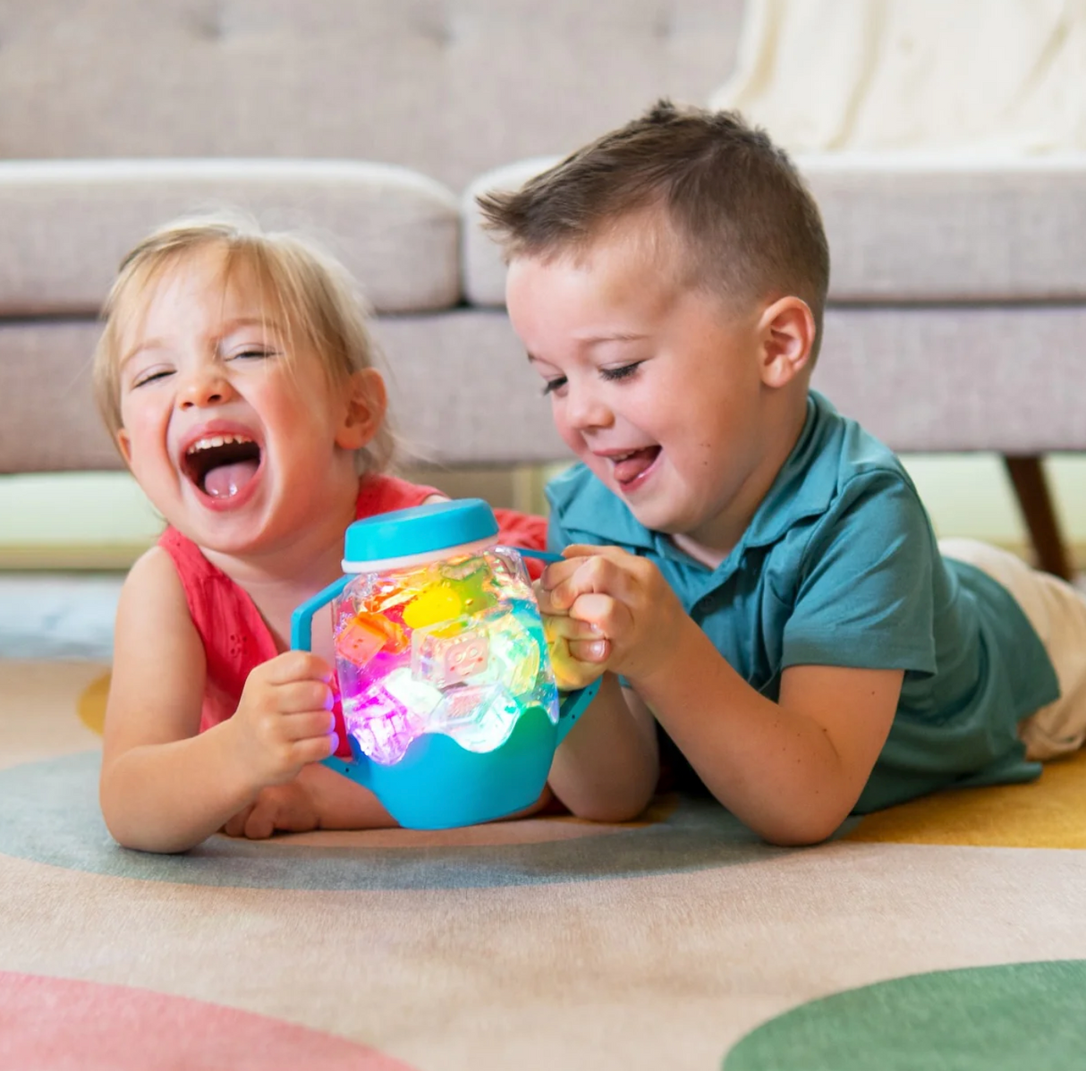 Two children playing with a colorful Sensory Jar | Purple that lights up and changes colors on the floor.