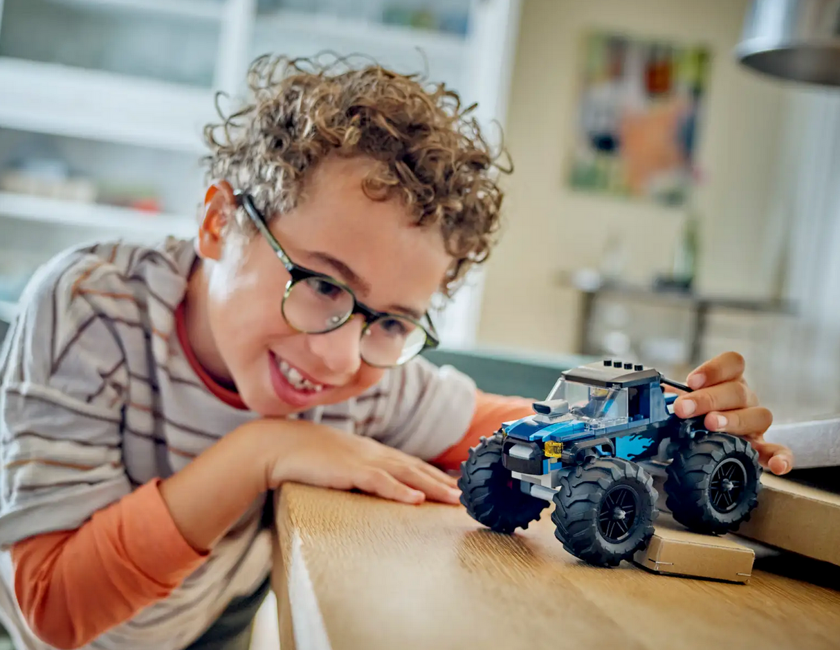 Child playing with the City Blue Monster Truck toy featuring large tires and a driver minifigure for imaginative play.