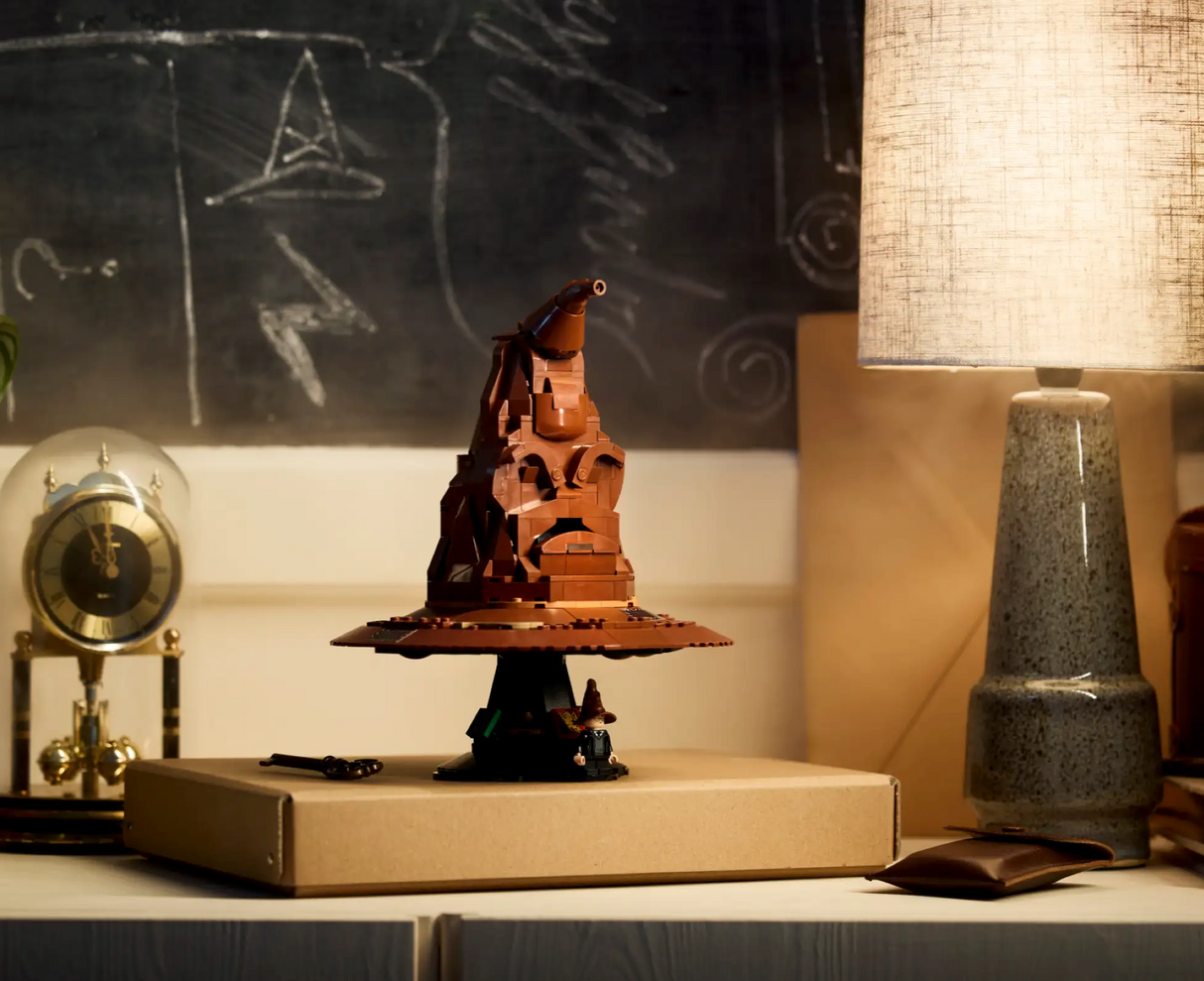 Harry Potter Talking Sorting Hat displayed on a box with a soft-lit lamp and vintage clock in the background.