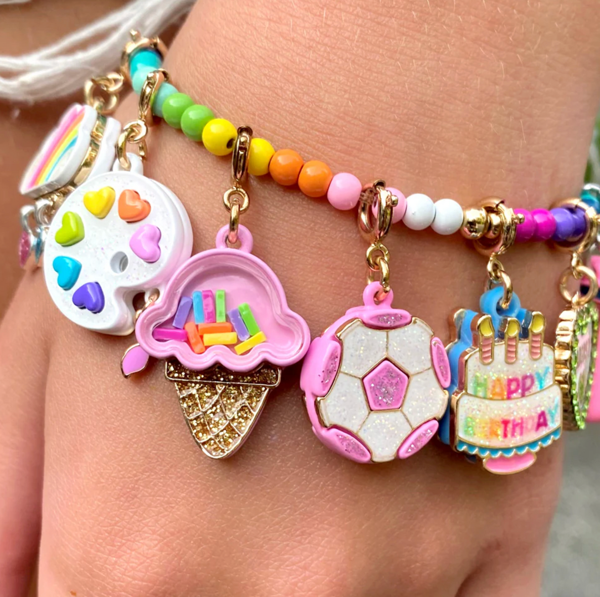 Gold Glitter Soccer Ball Charm with pink enamel and glitter, hanging on a colorful bead bracelet.