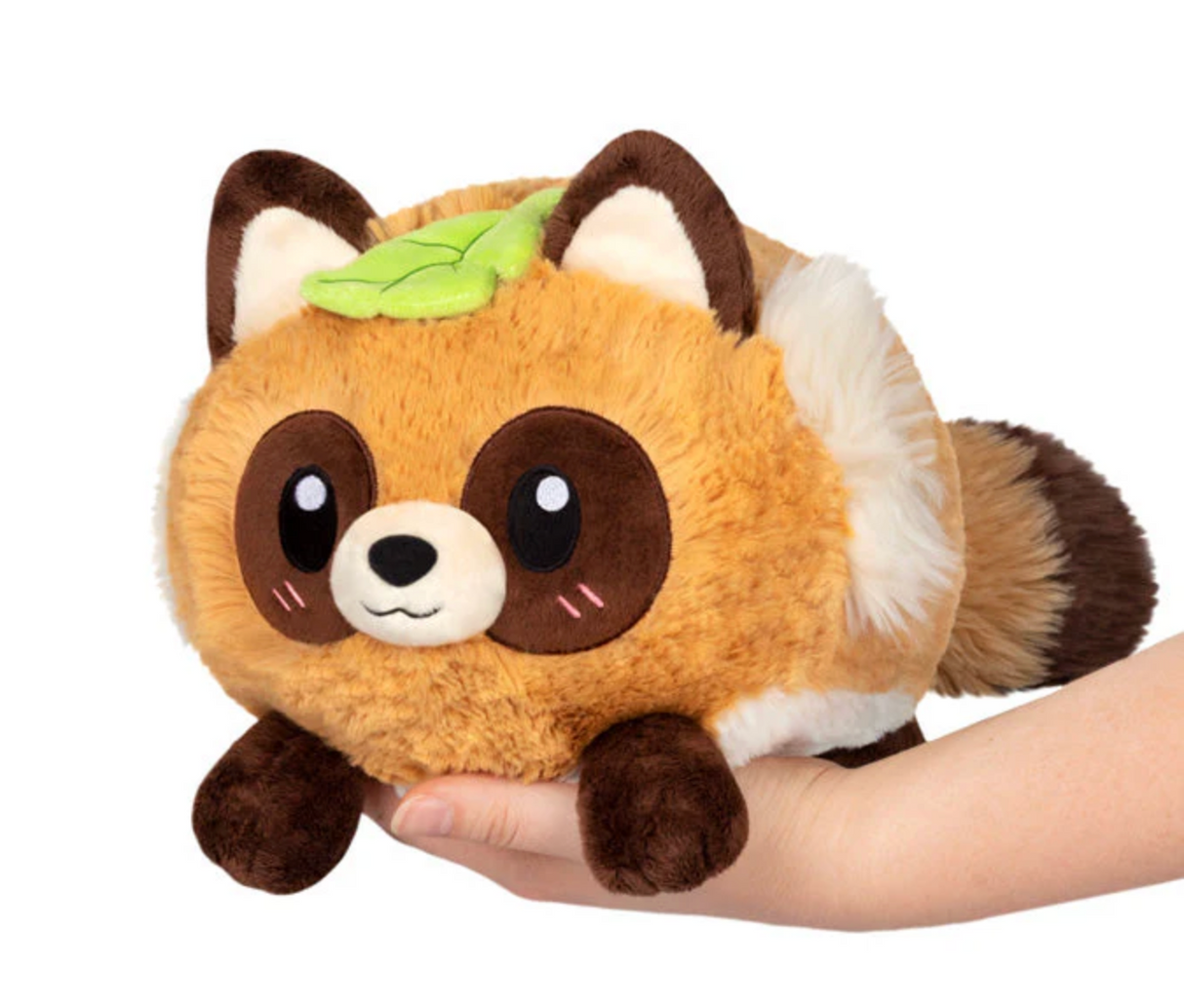 Hand holding a cute, plush Tanuki Mini toy with a leaf on its head and soft brown and white fur.
