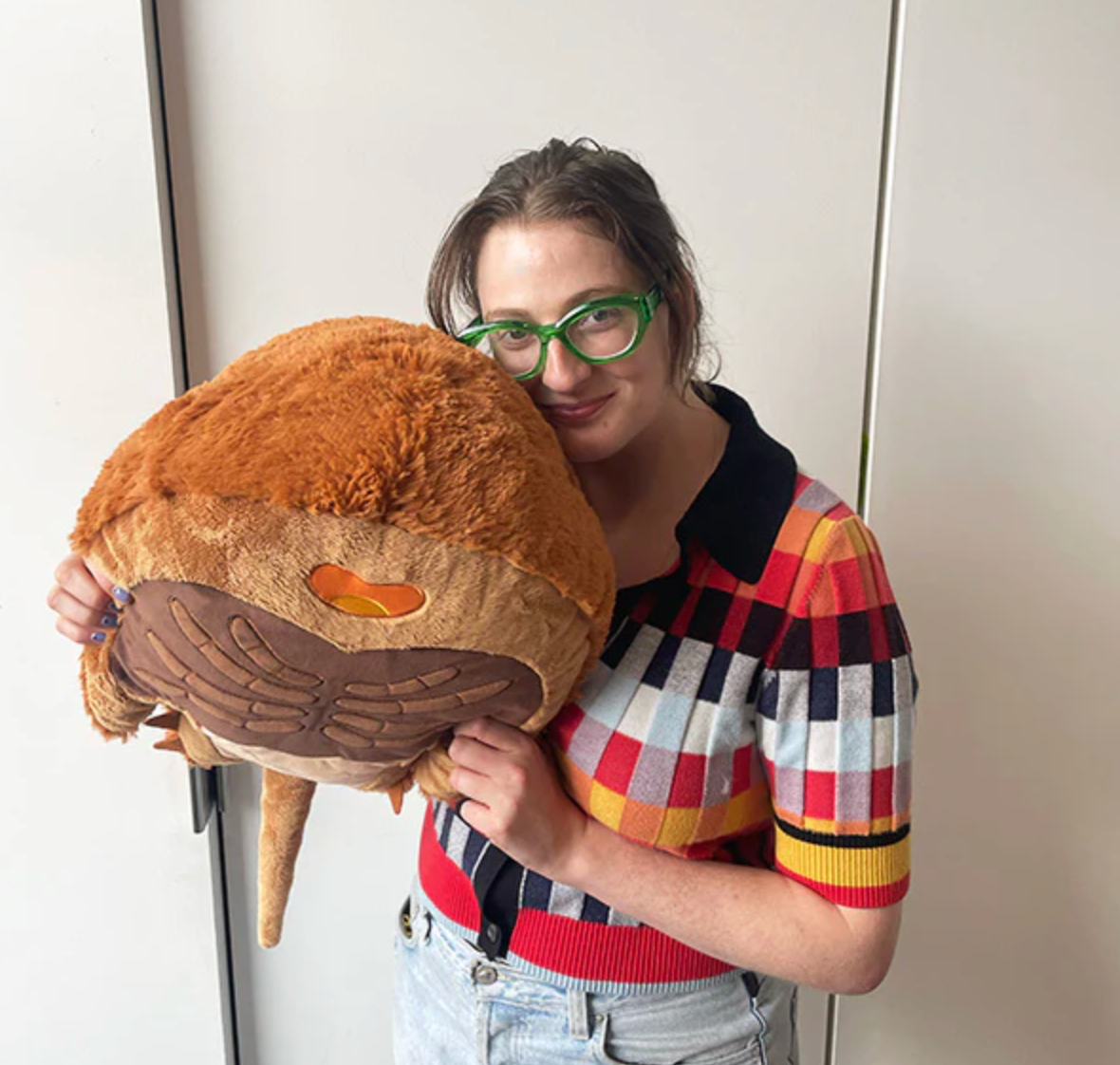 Woman holding a large, soft plush Horseshoe Crab toy measuring 14x24x10 inches made of polyester fiber.