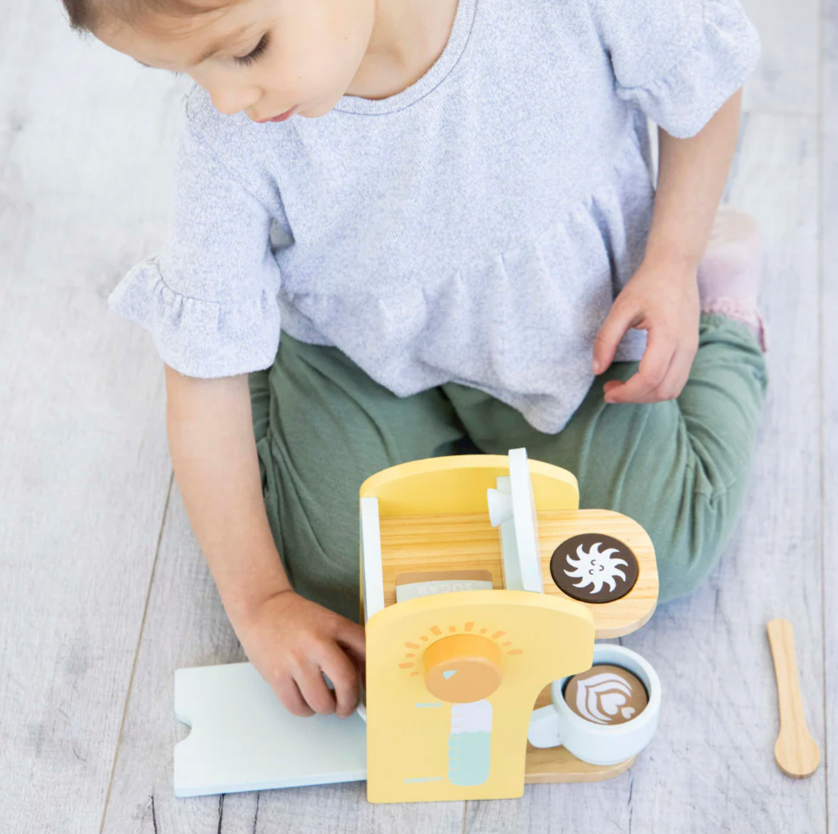 Child playing with the Barista in Training Wooden Coffee Set featuring a yellow coffee maker and accessories.