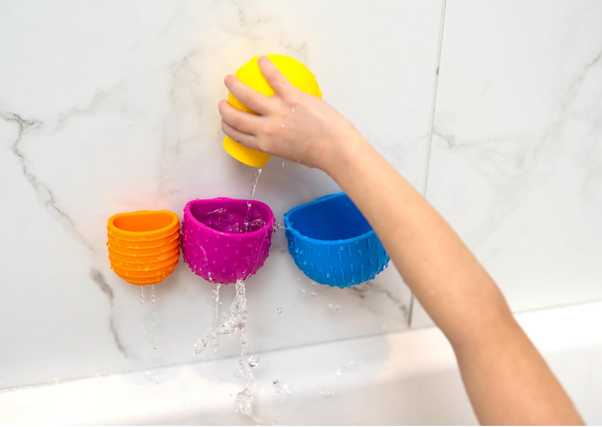 Child playing with colorful Oomplz Drip Drop Suction Cups attached to bathtub wall during water play.