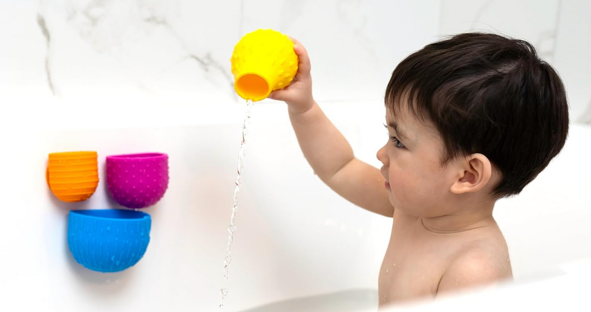 Child playing with colorful Oomplz Drip Drop Suction Cups in the bathtub for fun and skill-building play.