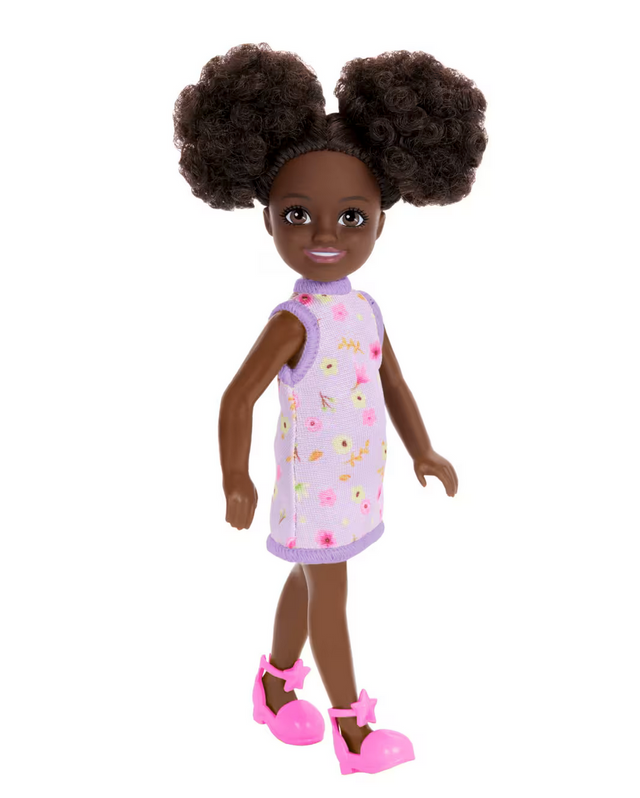 Barbie Chelsea #96 doll with curly space buns, purple floral dress, and pink star shoes, standing against white background.
