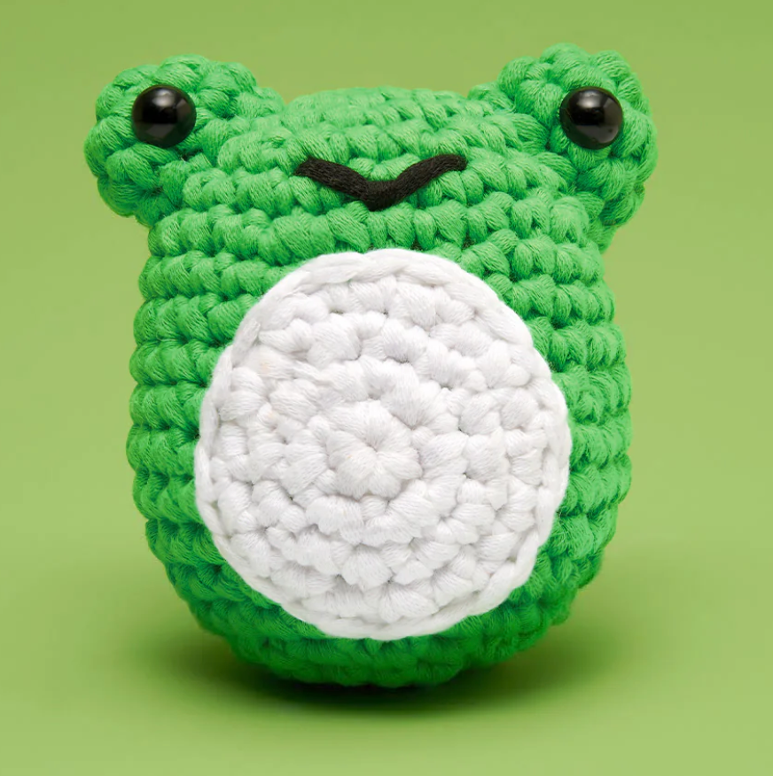 Woobles Crochet Kit | Henri the Frog showing a cute green crocheted frog face with black eyes on green background.