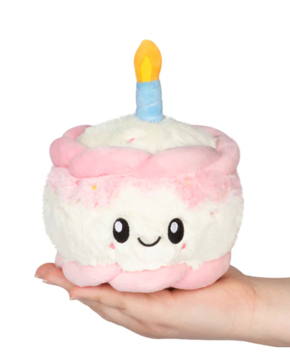 Happy Birthday Cake Snackers plush toy with smiling face, pink icing, and blue candle held in hand.