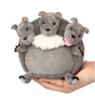 Hand holding Cerberus Snackers plush toy with three gray dog heads showing different expressions in soft fabric.