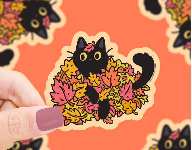 Autumn Kitty Leaves Sticker showing a black cat playing joyfully in colorful autumn leaves, weatherproof and scratch resistant.