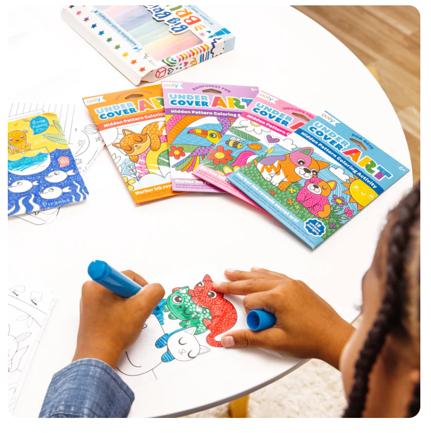 Child coloring animal illustrations from Undercover Art | Rainforest Fun hidden pattern activity set on a round white table.