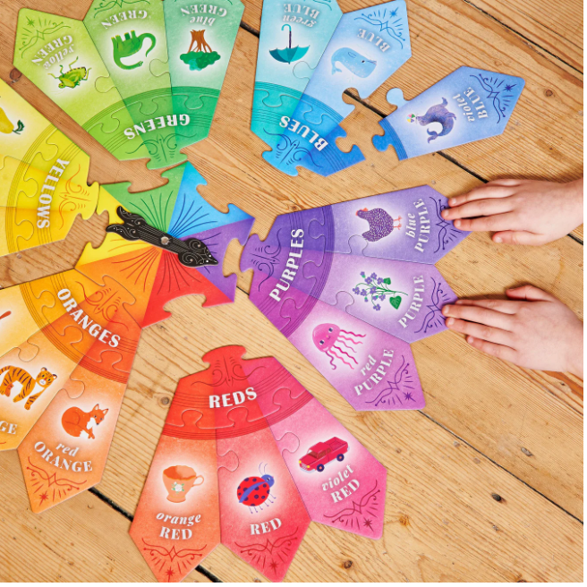 Color Puzzle Spinner Game showing colorful puzzle pieces and a hand placing purple pieces on a wooden surface.