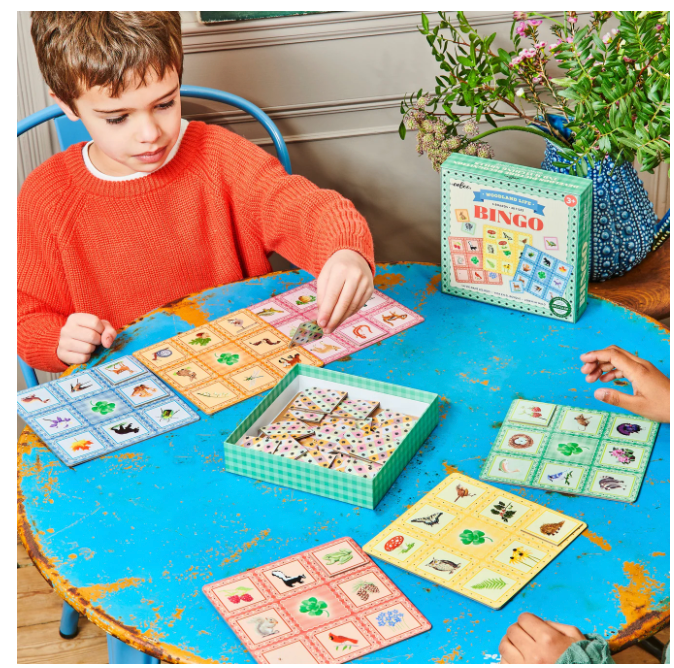 Busy Woods Bingo game with woodland creature boards and tiles played by children at a blue table.