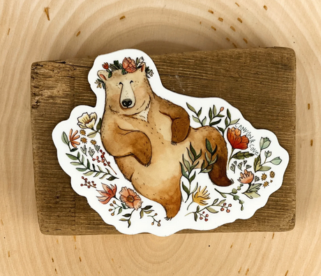 Bear in Flowers Sticker featuring a relaxed bear surrounded by colorful floral designs on a matte vinyl finish.