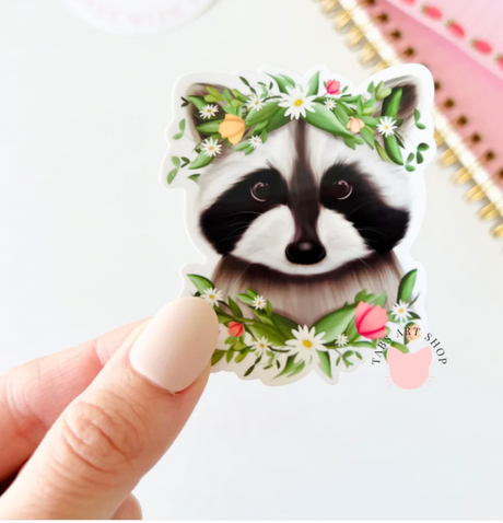 Spring Raccoon Sticker featuring a raccoon with a flower crown, perfect for laptops and notebooks, glossy vinyl, 2x3 inches.