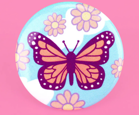 Monarch Butterfly Button featuring a vibrant orange butterfly with purple accents on a blue background with flowers.