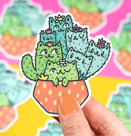 Hand holding Cat Catus Garden Sticker featuring cute cactus-shaped cats in a polka dot pot, weatherproof and scratch resistant.