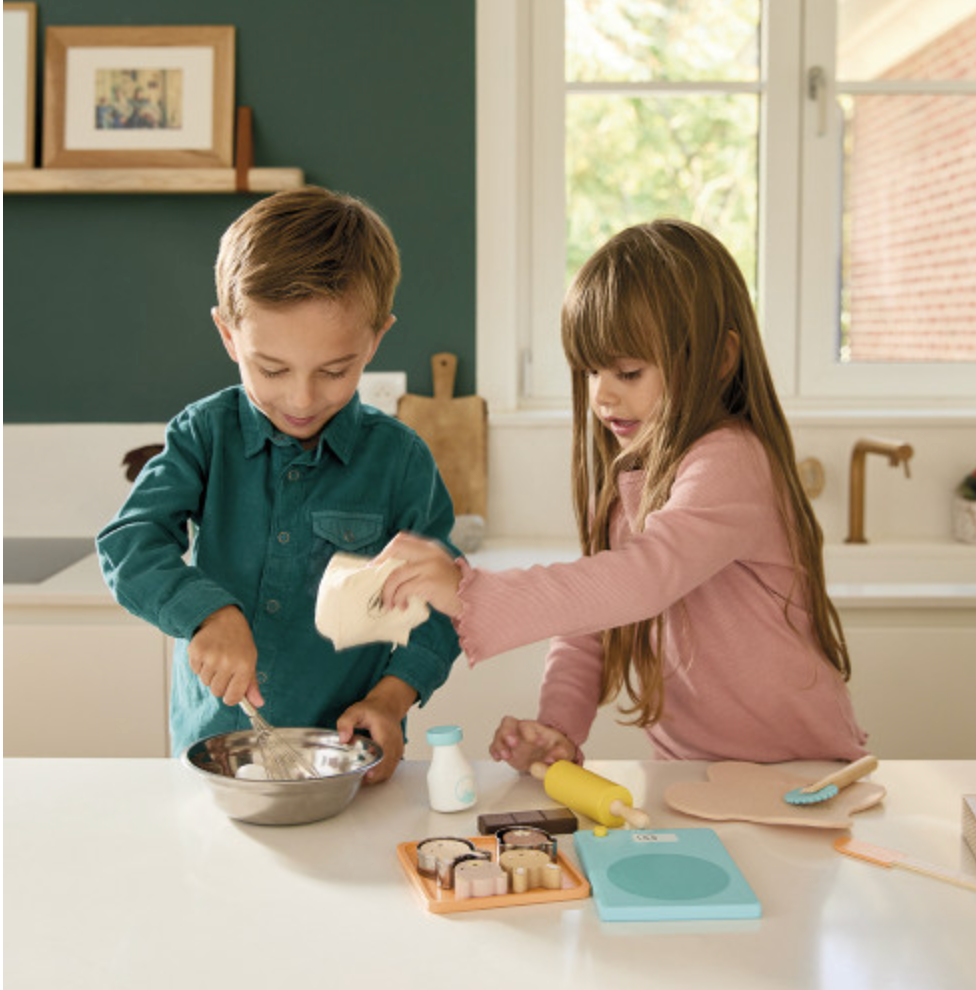 Two children playfully baking together with utensils and ingredients in a kitchen, enjoying My Pastry Workshop.