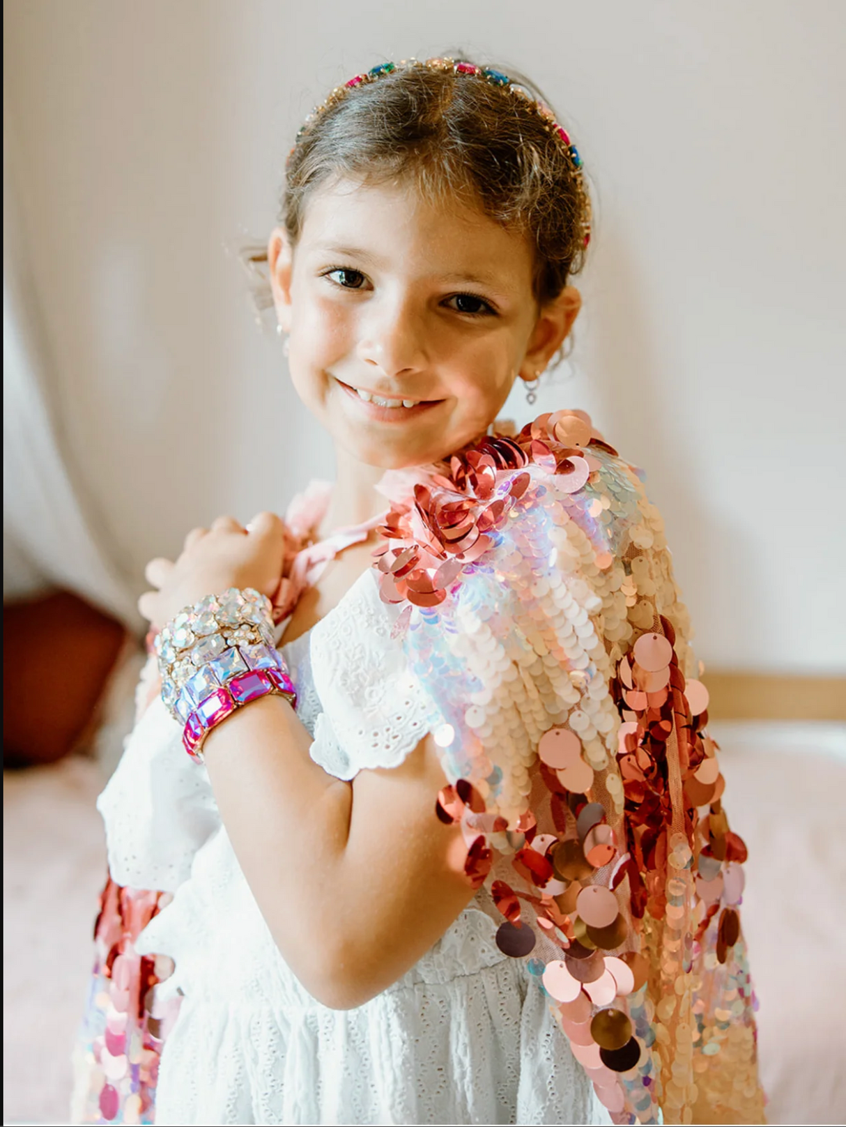 The 5th Avenue Pailette Cape | Pink worn by a smiling girl with large and small pink sequins and tulle collar.