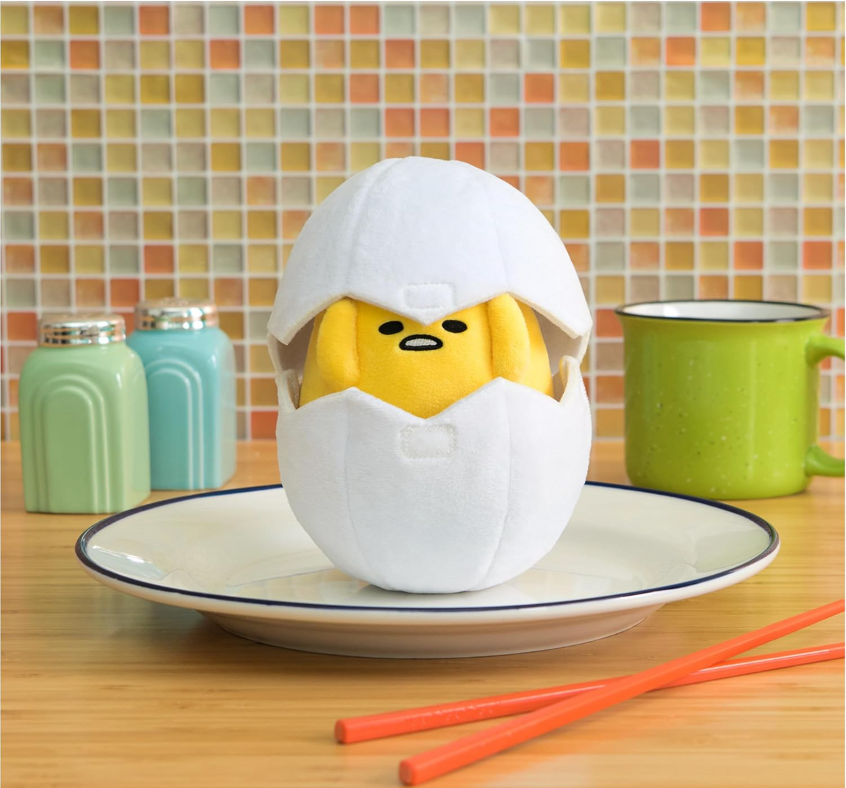 Gudetama in Eggshell plush toy sitting on a plate with a soft white shell and alarmed yolk expression.