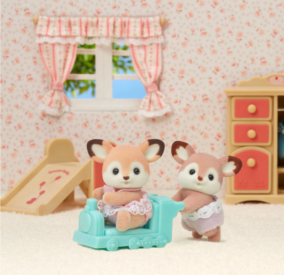 Deer Twins with adorable big ears and different colors, one twin sitting in a blue pushcar in a cozy playroom.
