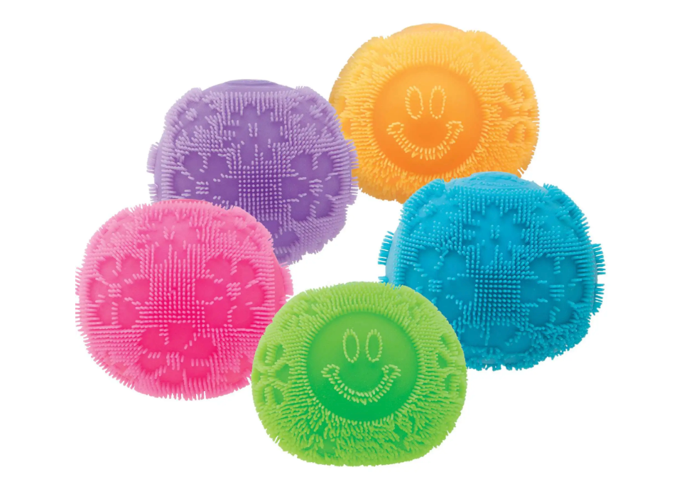Colorful assorted NeeDoh Fuzz Ball Flower Power stress balls with smiley faces and flower patterns for squeezing and relaxation.