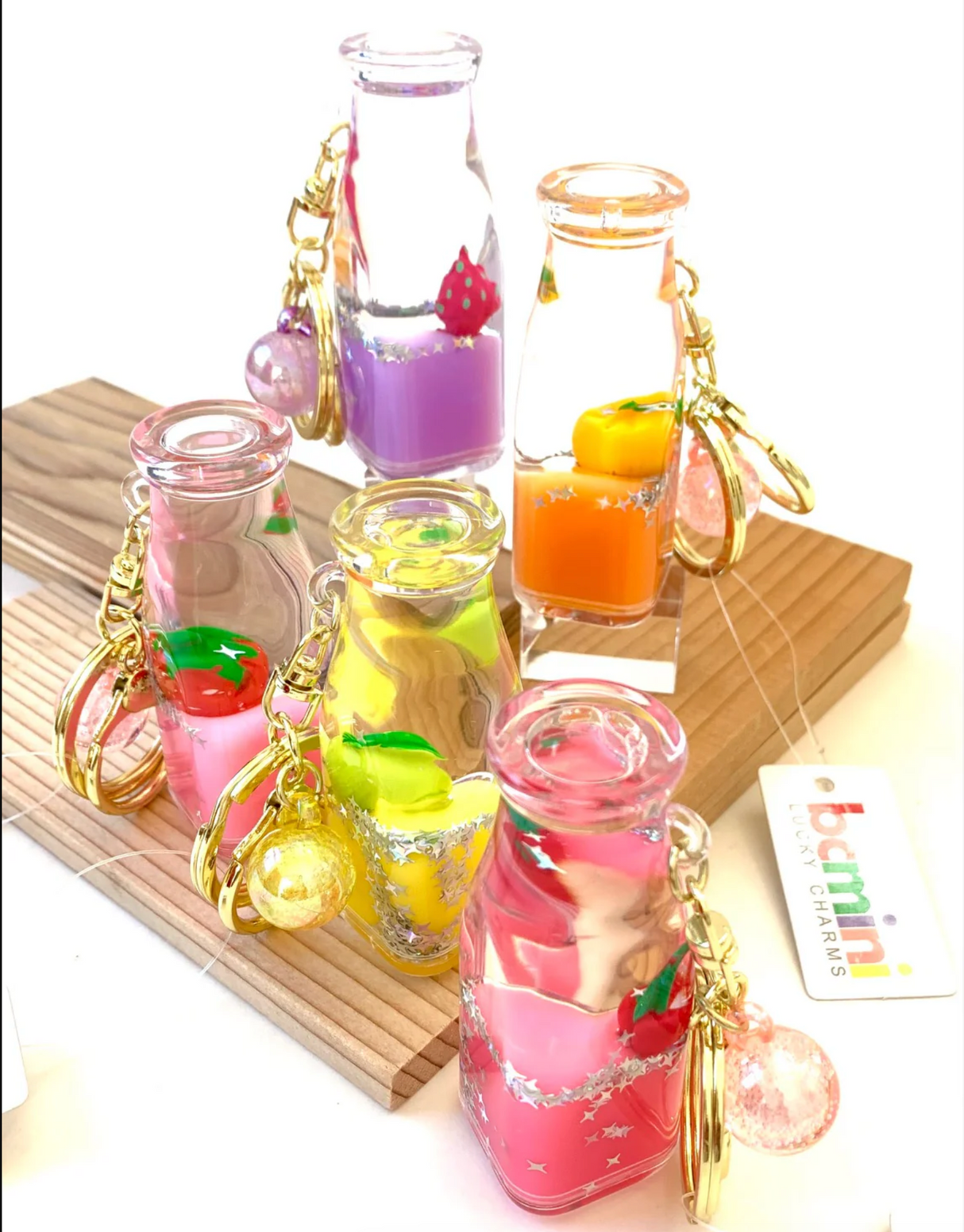 Fruit Bottle Floaty KeyChain with colorful fruit designs floating inside clear bottles on gold key rings.