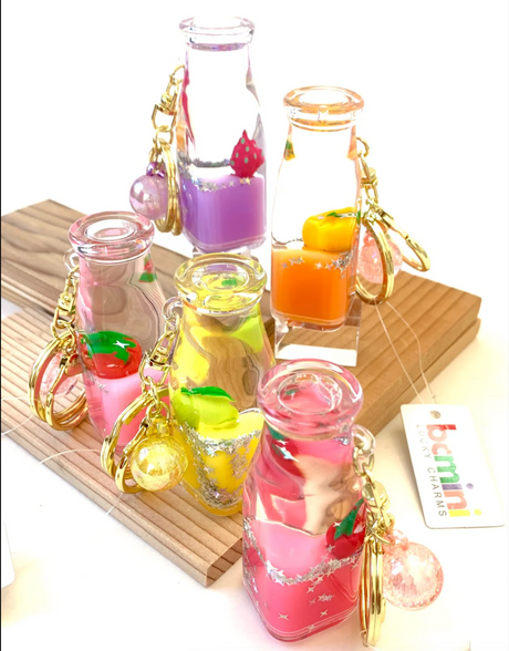 Fruit Bottle Floaty KeyChain with colorful fruit designs floating inside clear bottles on gold key rings.