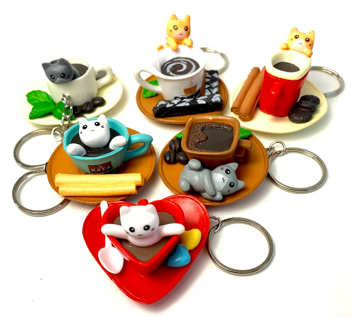 Colorful Cat Cafe KeyChain set featuring playful cats in coffee cups and saucers with cookies and cinnamon sticks.