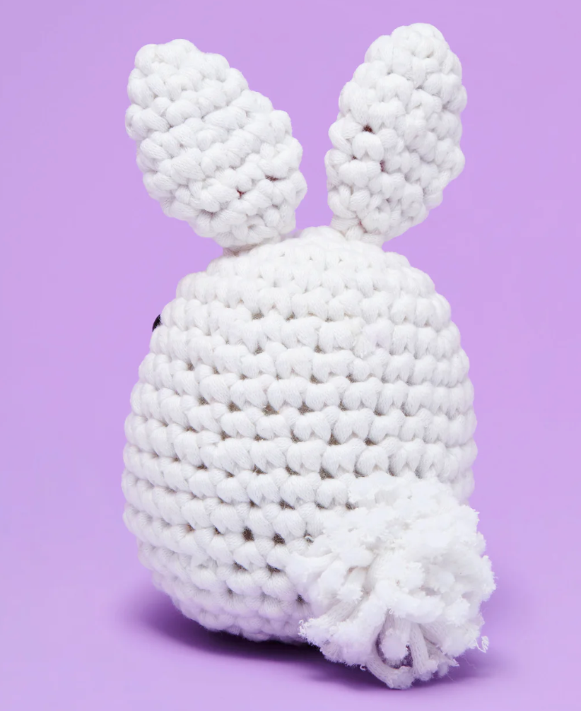 The Woobles Crochet Kit | Jojo the Bunny shows a handmade white crocheted bunny with ears and a fluffy tail on a purple background.
