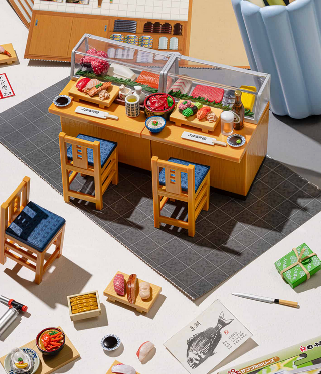 Re-Ment | Sushi Restaurant Blind Box showing detailed miniature sushi counter with dishes, chairs, and accessories in a diorama setup.