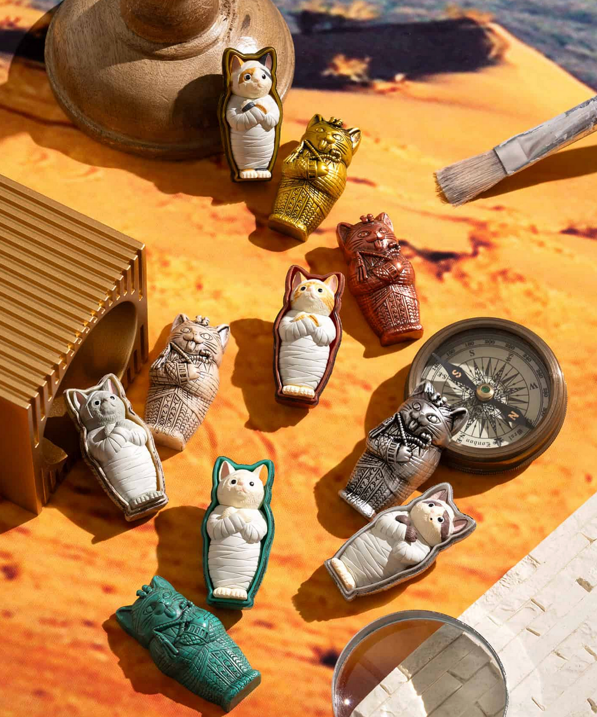 Mummy Cat Blind Box featuring collectible cat figures in colorful ancient coffin designs arranged on a desert-themed background.