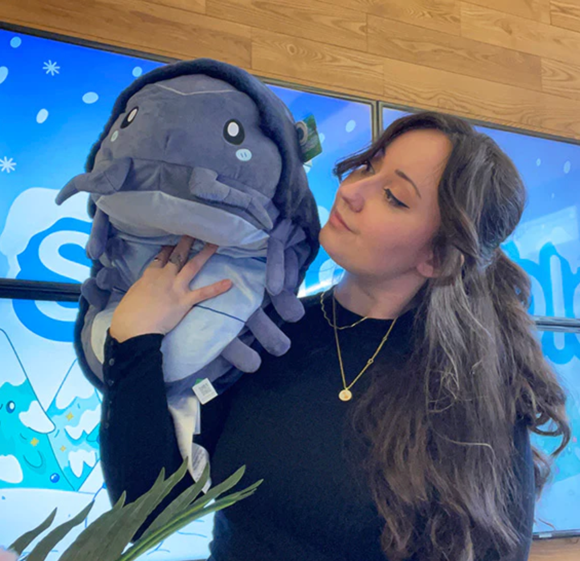Woman holding a soft plush toy of the Pillbug Roly Poly, a foldable stuffed bug with magnets to roll up.