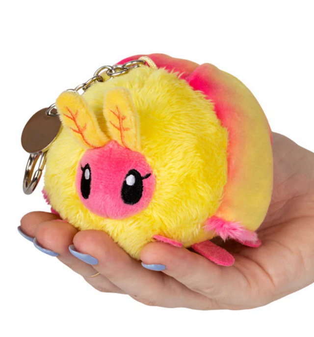 Rosy Maple Moth Micro plush keychain with metal clip, held in hand, soft yellow and pink colors.