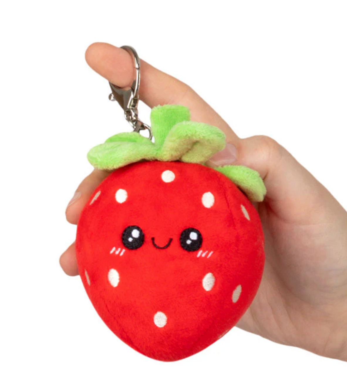 Hand holding a Strawberry Micro plush toy with a cute face and metal clip keychain attached.