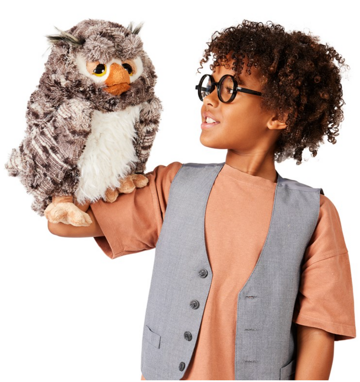 A child wearing glasses holds the Wise Owl Puppet, a soft poly plush owl with a movable beak and winking eyebrow pockets.