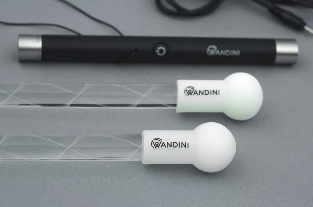 Close-up of Wandini Glow Wand LED light wand with black controller and glowing white tips on transparent rods.