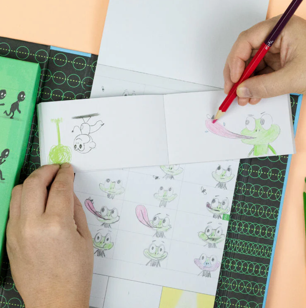 Hands drawing animated characters in a flip book from the Flip Book Kit | Animation in Action for kids learning animation.