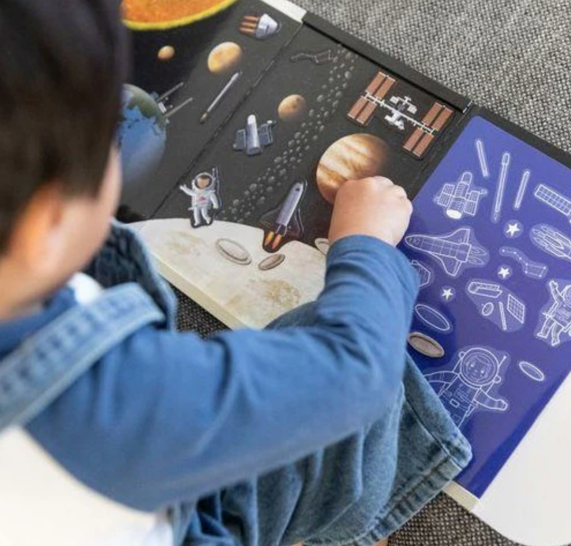 Child playing with Magna Carry | Space Explorer magnetic space scene featuring rockets, planets, and astronauts on a fold-out playset.