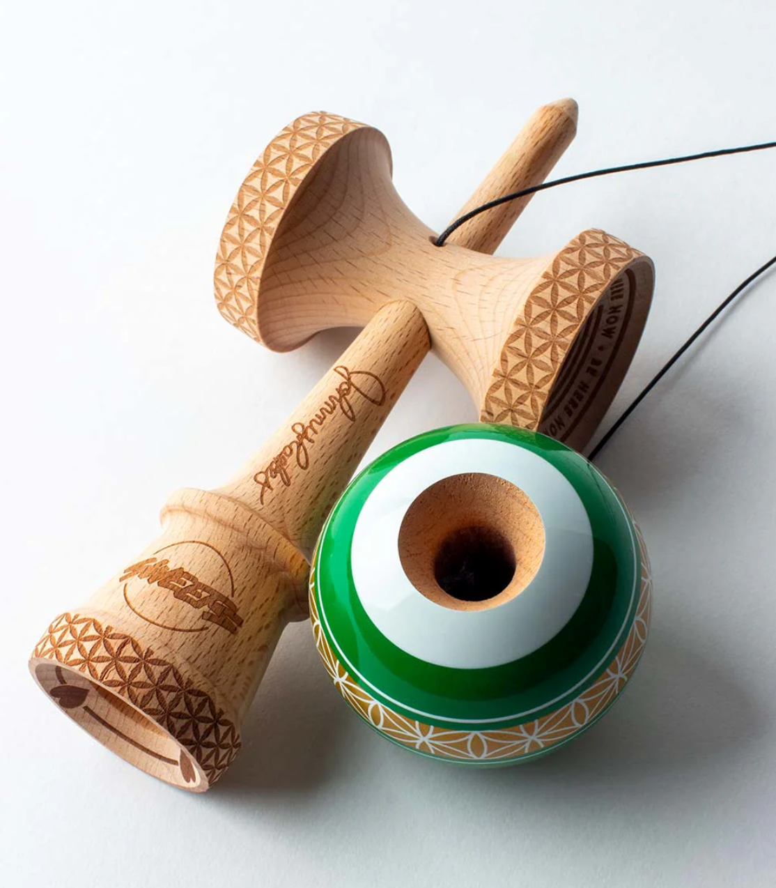 Kendama Johnny Raekes V2 BS Sticky with wooden handle and green and white tama featuring intricate geometric patterns.