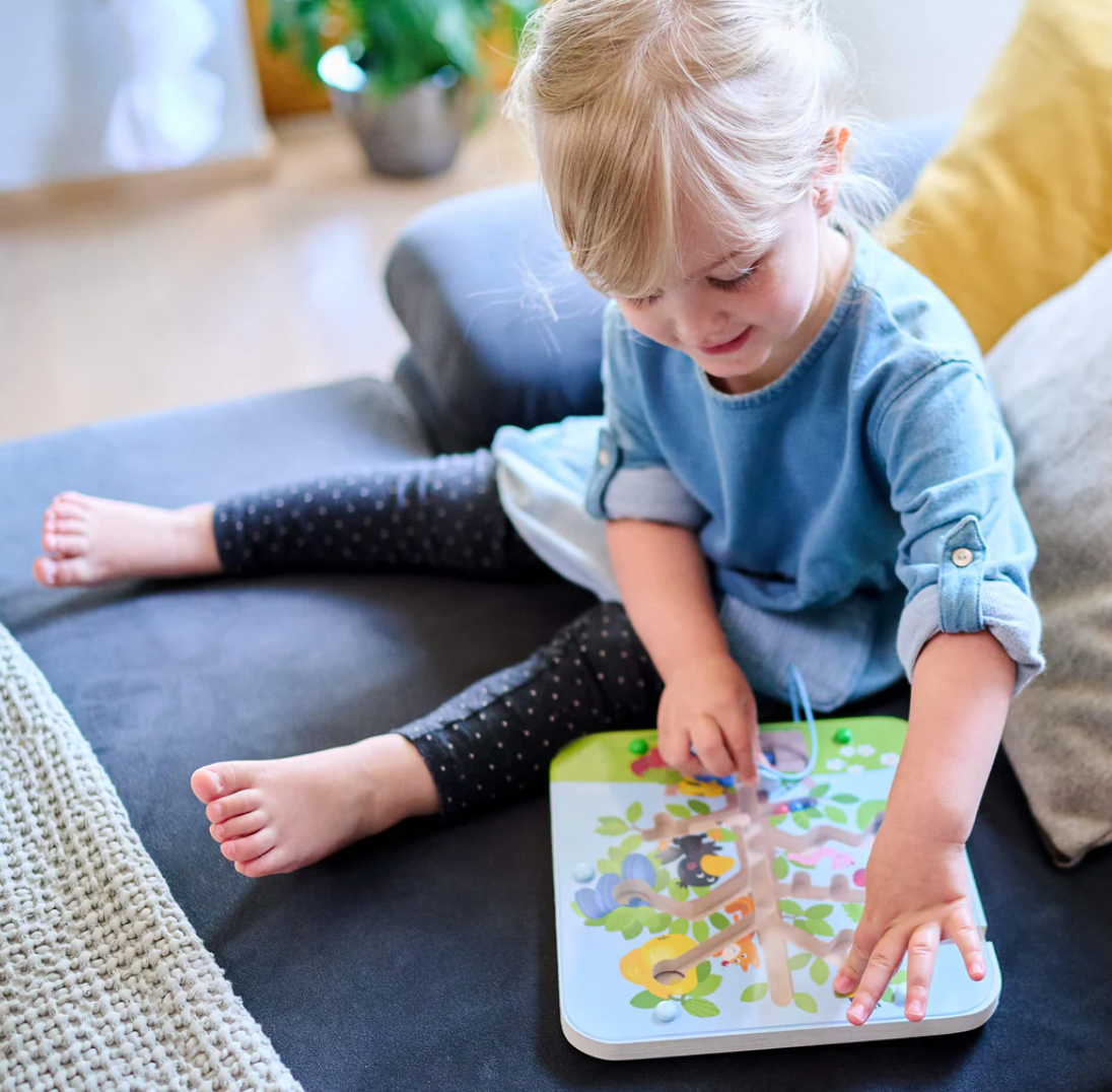 Child playing with Magnetic Sorting Game | Orchard Maze using the magnetic wand to move colorful fruit balls on the board.
