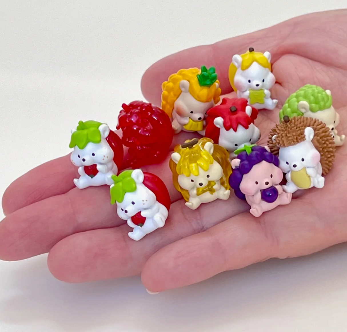 Mini Hedgehog Fruits Blind Box showing a hand holding multiple cute fruit-themed hedgehog figurines.