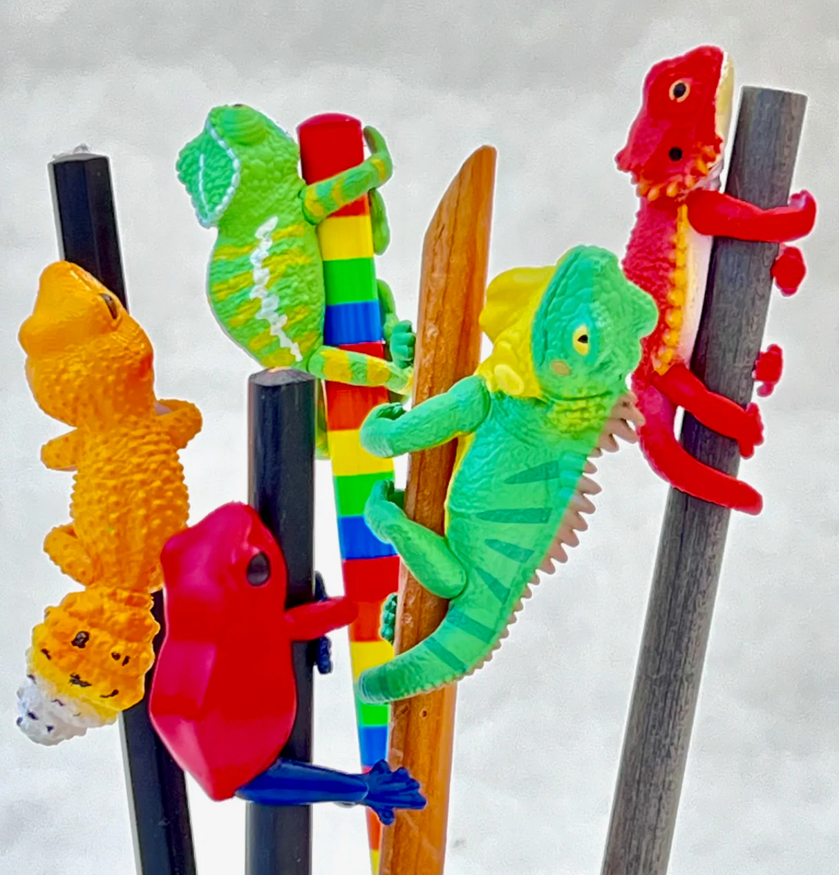 Colorful lizard toys clinging to sticks, showcasing the playful surprise inside the Lizard Blind Box.