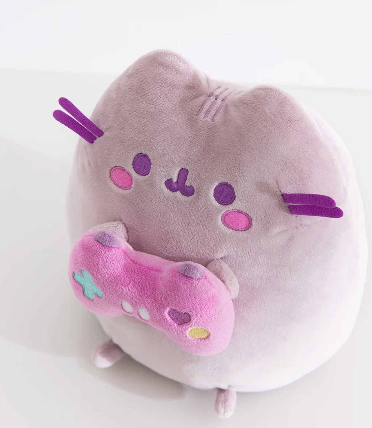 Pusheen Gamer plush in soft purple holding a bright pink controller with embroidered details, perfect cute gaming partner.