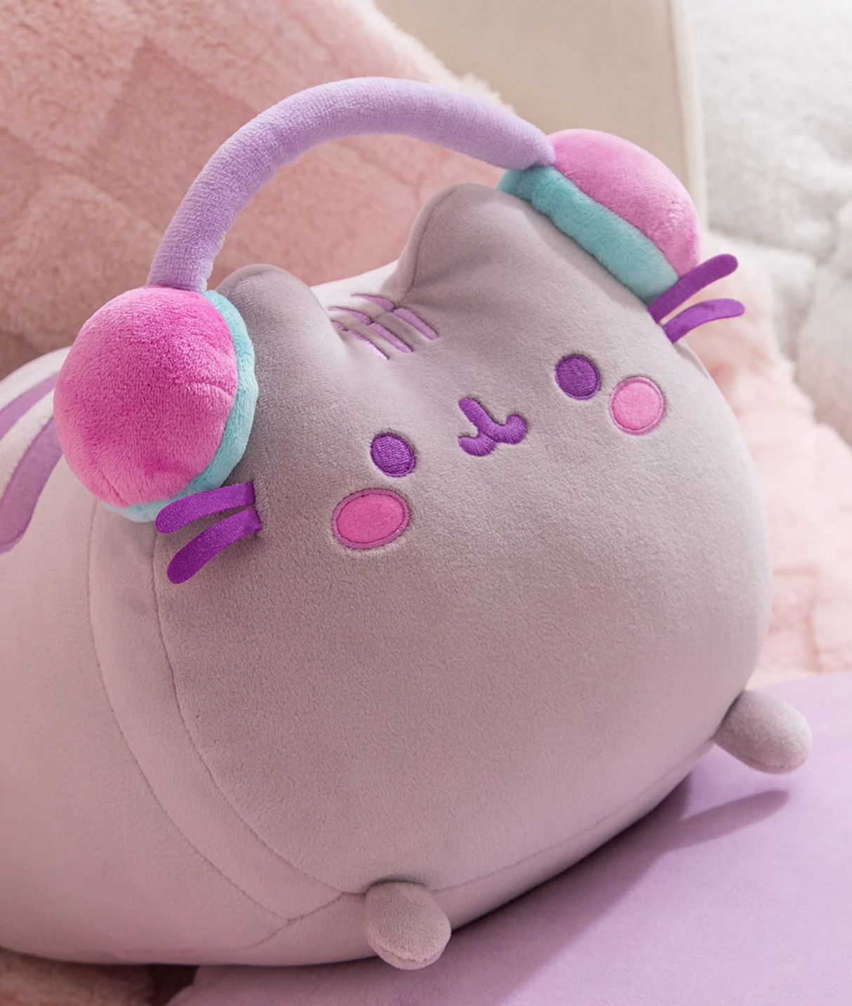 Pusheen Gamer Log Squisheen plush with purple-striped headphones and pink cheeks in a relaxed gaming pose.