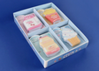 Set of four snack-shaped erasers including milk, fries, bread, and ice cream in a divided box on a blue background