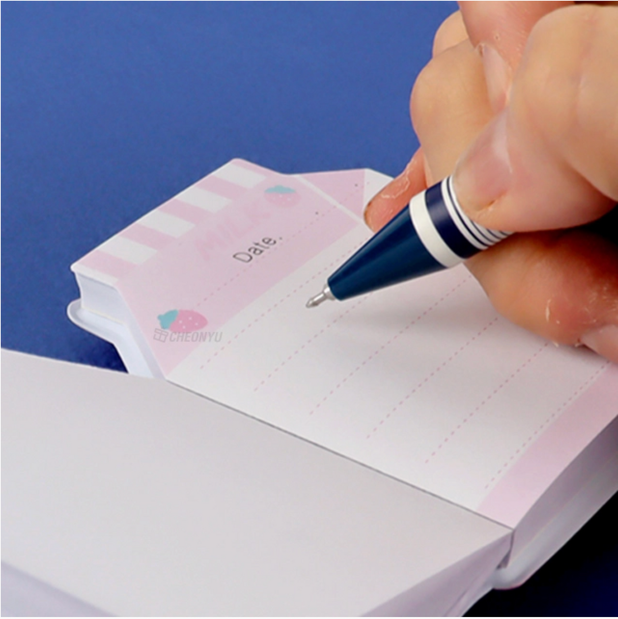 Close-up of a hand writing on a pink, milk carton-shaped note from the My Favorite Snack Notebook set