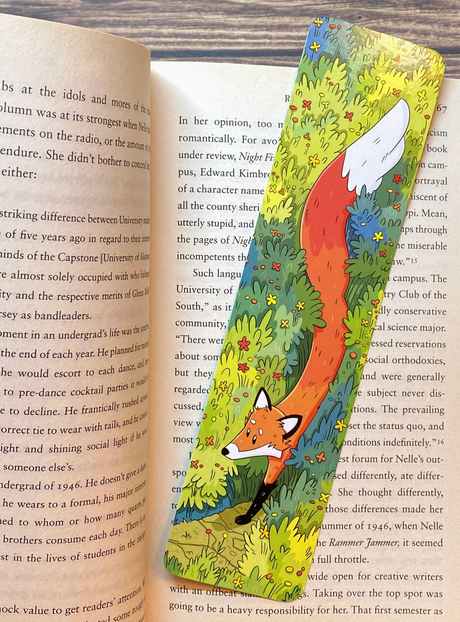 Colorful bookmark featuring a red fox walking through tall wild grasses with flowers on a wood surface background